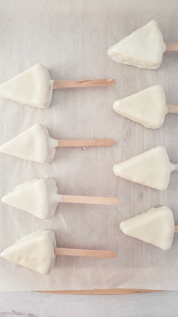White dipped cheesecake slices on parchment paper