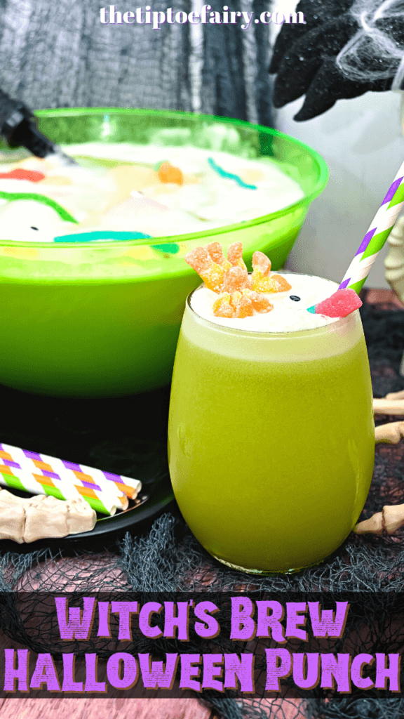 Close up of glass of our green Witch's Brew Halloween Punch topped with an orange spider and a red gummy worm and a candy eye with purple and green straws in front of a bowl of punch. 
