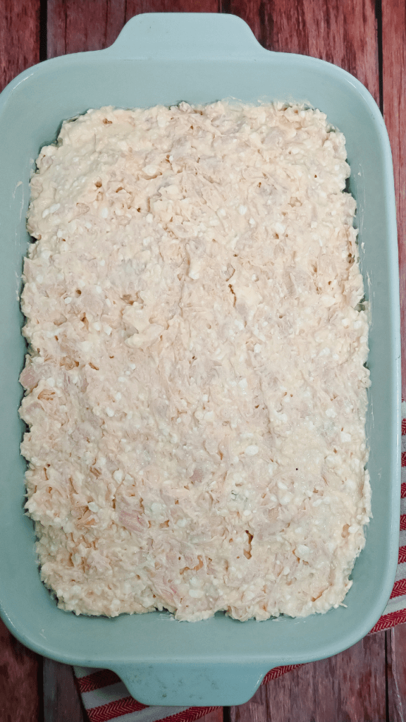 Chicken mixture spread out in the blue casserole dish. 