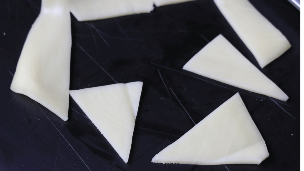 Triangular slices of mozzarella cheese on a black plate. 