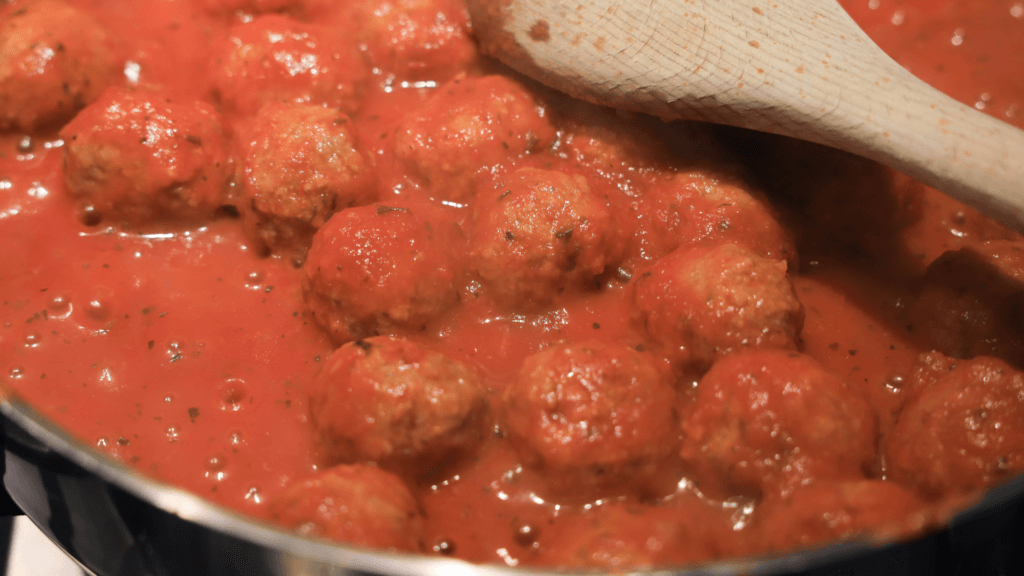 Warmed up and bubbling spaghetti sauce with cooked meatballs ready for the sliders. 