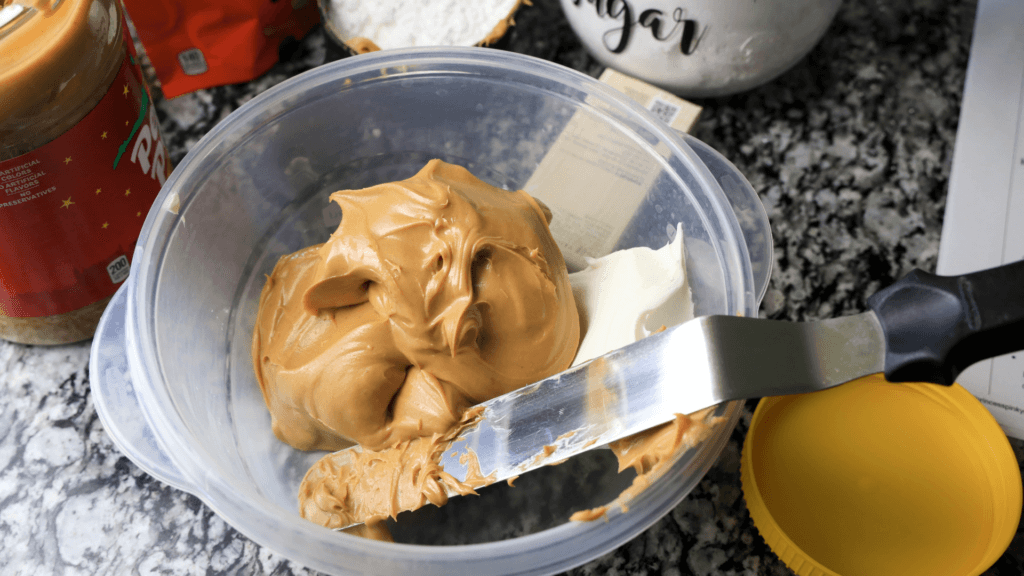 Adding the peanut butter, vanilla, and cream cheese to a plastic bowl and getting ready to mix it up. 