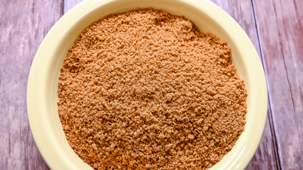 A yellow bowl full of biscoff cookie crumbs. 