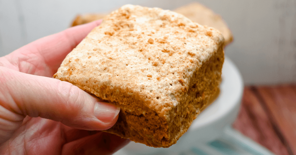 A woman's hand holding up a Biscoff Cookie Marshmallow Bar. 