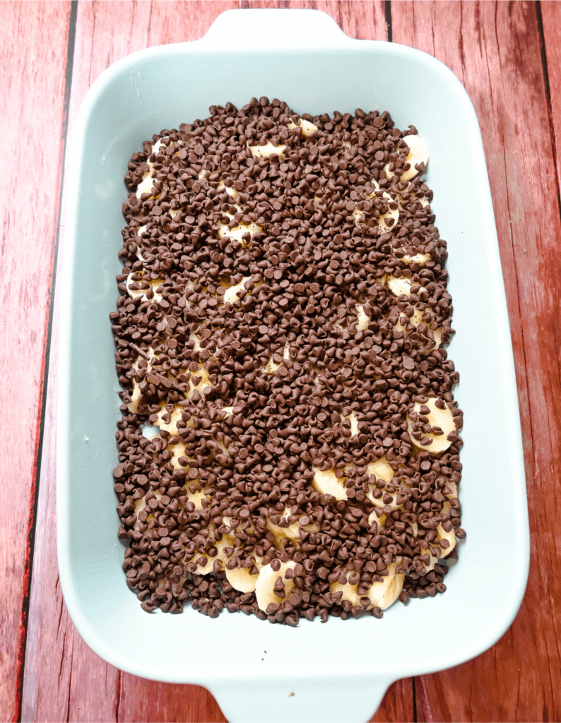 Chocolate chips over bananas in a light blue casserole dish