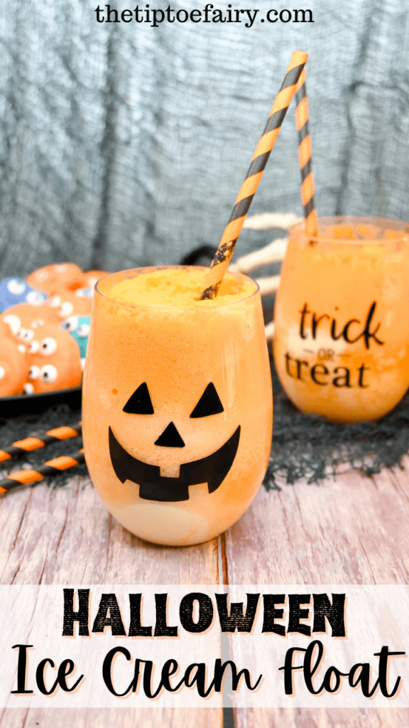 A jack o'lantern stemless wineglass full of orange soda and vanilla ice cream to make Halloween Ice Cream Floats with another in the background as well as a plate of monster cookies. 