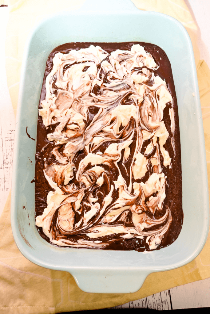Brownie batter and cheesecake batter swirled together in the pan
