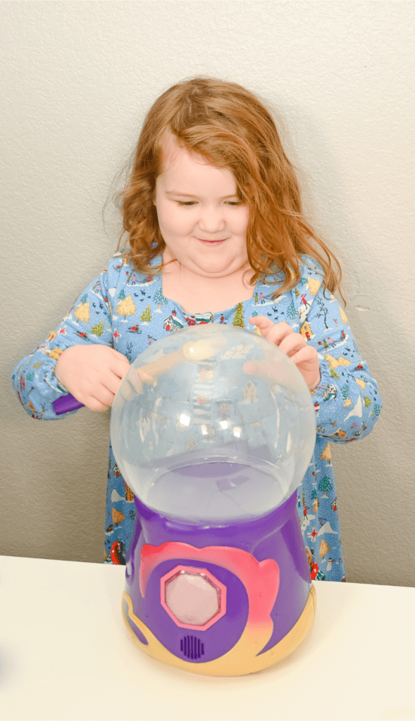 A little girl waving a magic wand over the Magic Mixies Magical Crystal Ball
