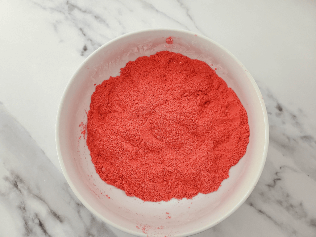 A white bowl with red kinetic sand on marble