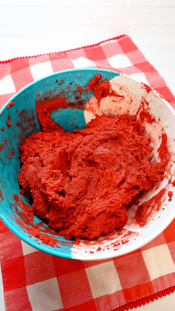 Red velvet cookie dough in a blue and white bowl on a red plaid placemat