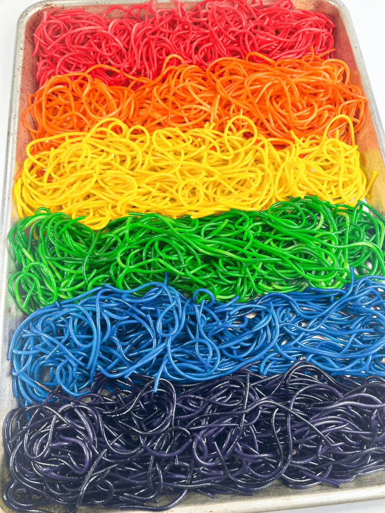 A sheet pan full of six colors of rainbow spaghetti pasta