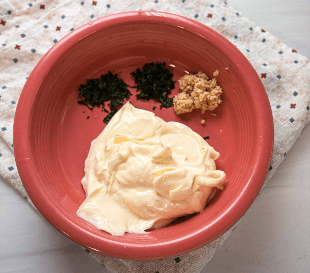 Ingredients in a pink bowl to make herbed mayonnaise