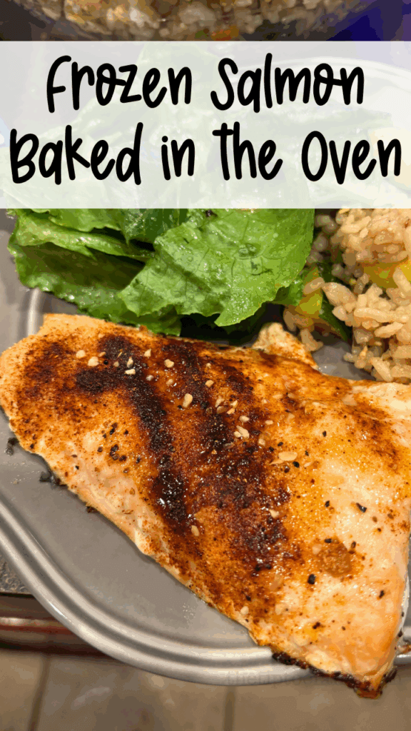 A close up of frozen salmon that's been baked in the oven with spices on a gray plate with rice and salad.