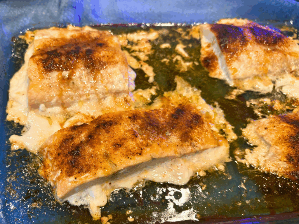 Finished salmon that was frozen and then baked in a blue casserole dish.