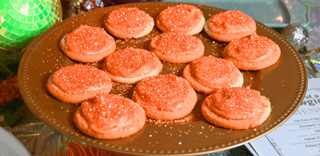 Close up of a gold plate with orange sugar cookies for the life of a showgirl Elizabeth Taylor track.